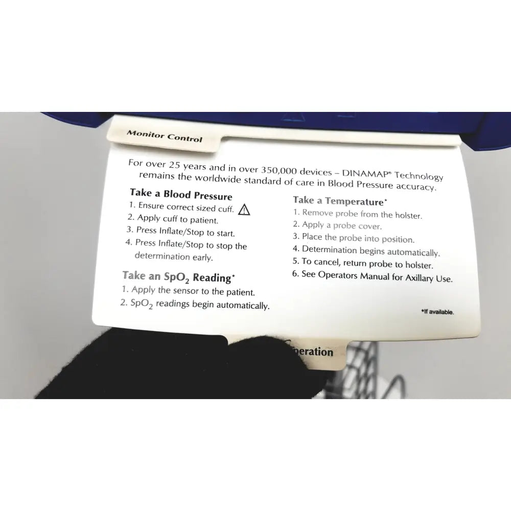 White paper label with black text detailing blood pressure and spo2 monitoring instructions for dinamap dcp400n-en patient monitor with rolling stand and basket