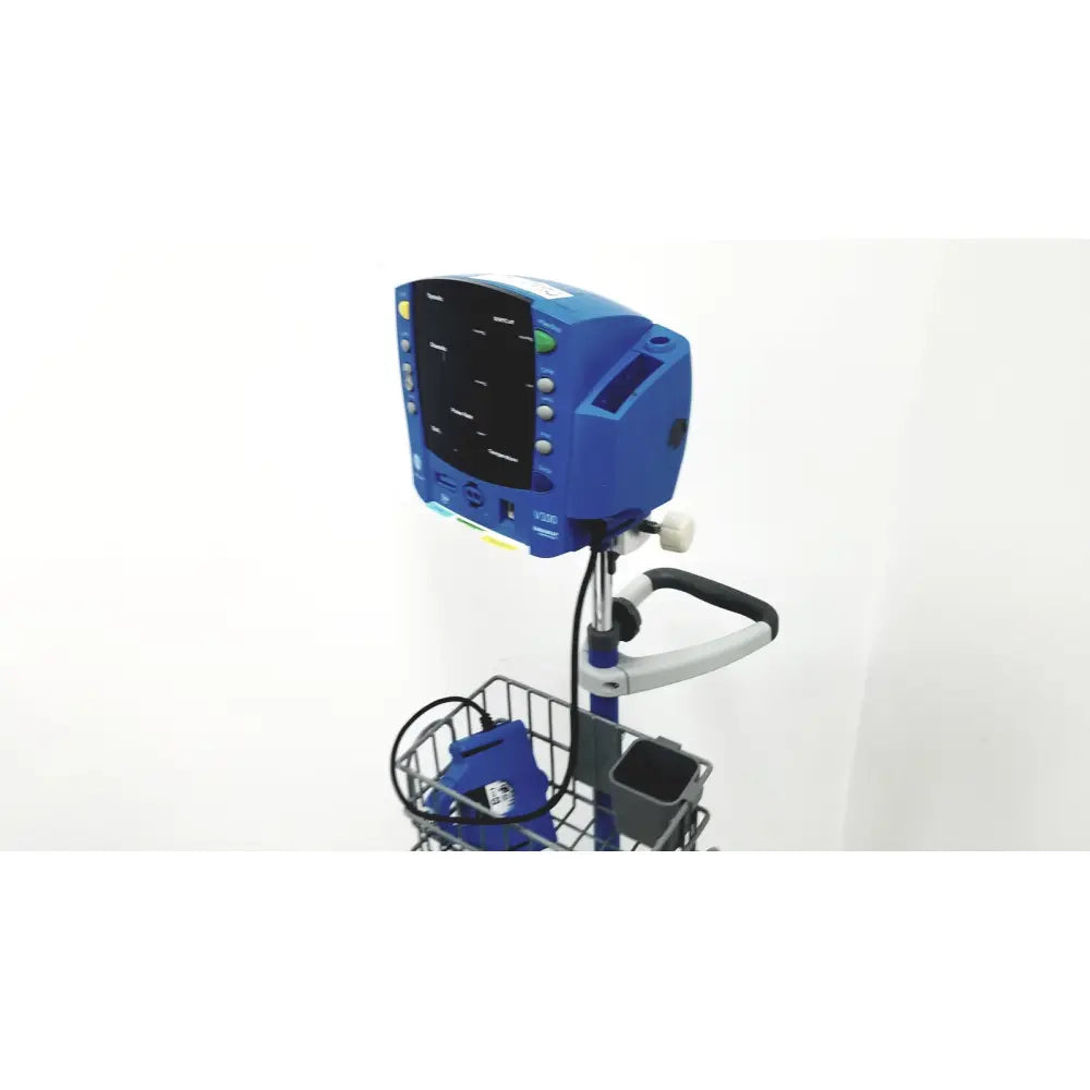 Blue dinamap v100 vital signs monitor mounted on a rolling stand with wire basket for medical use