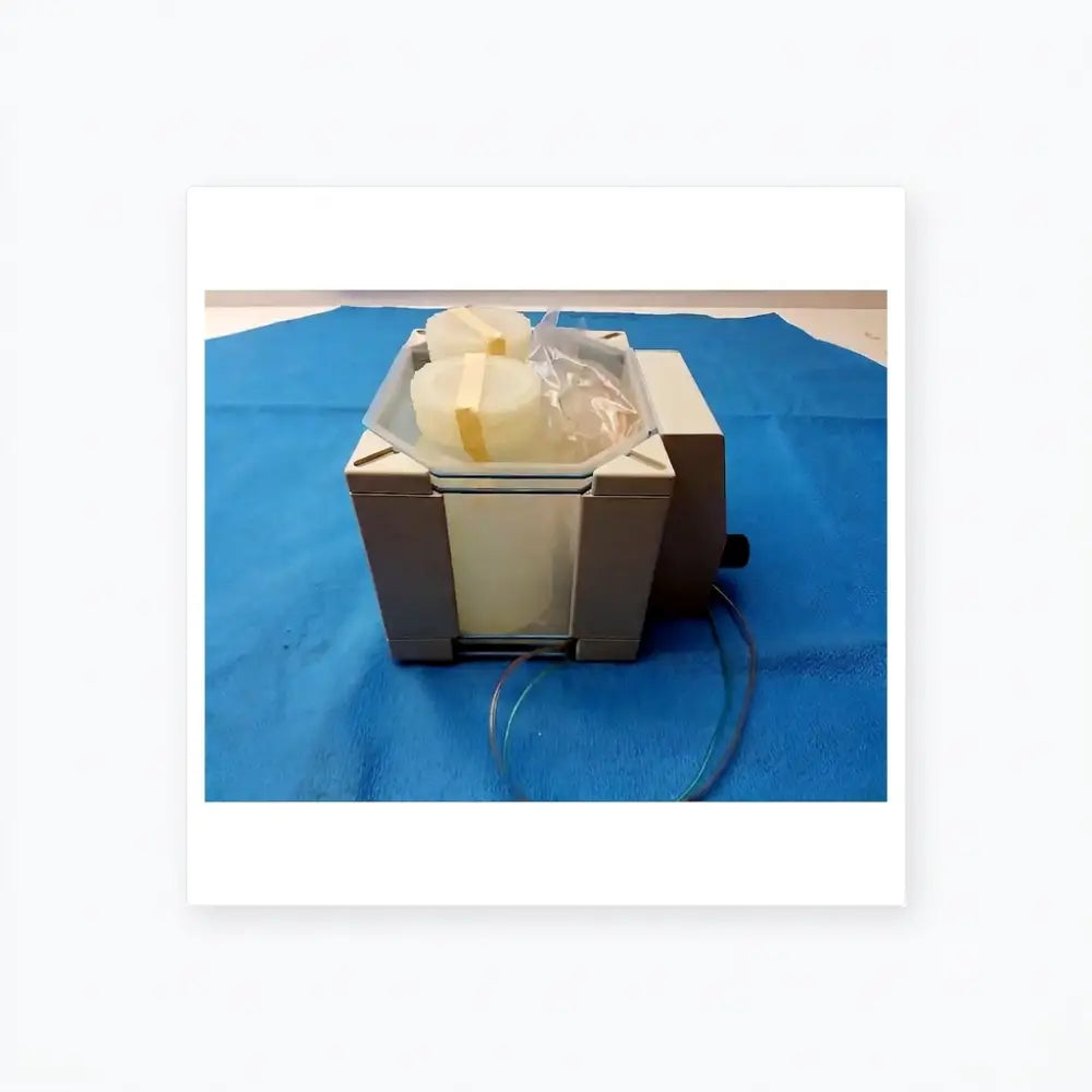 Gray rectangular laboratory dionex pc-10 pneumatic controller with clear container holding two pale yellow wrapped cylinders