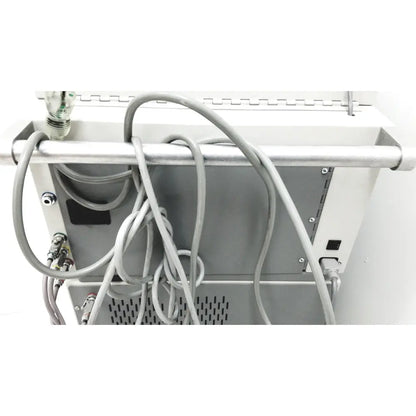 Gray coiled cables hang from the metallic bar at the back of the white dntl works p-2000 dental delivery unit with midwest rhino