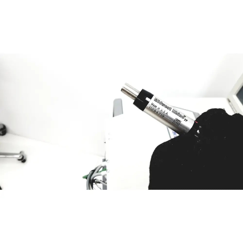 A sleek silver kitchener eithna xp torque wrench with black grip held in a gloved hand for dntl works dental delivery unit