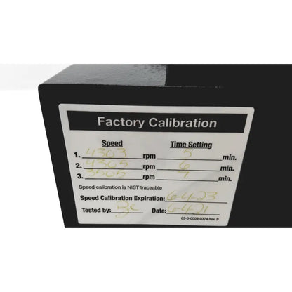 Black industrial machine with white factory calibration label showing handwritten data and nist traceable certification on drucker diagnostics dash apex 24 centrifuge