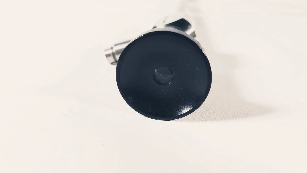 Black circular cap with central hexagonal bolt attached to metallic parts of dyonics autoclave degree 10mm laparoscope