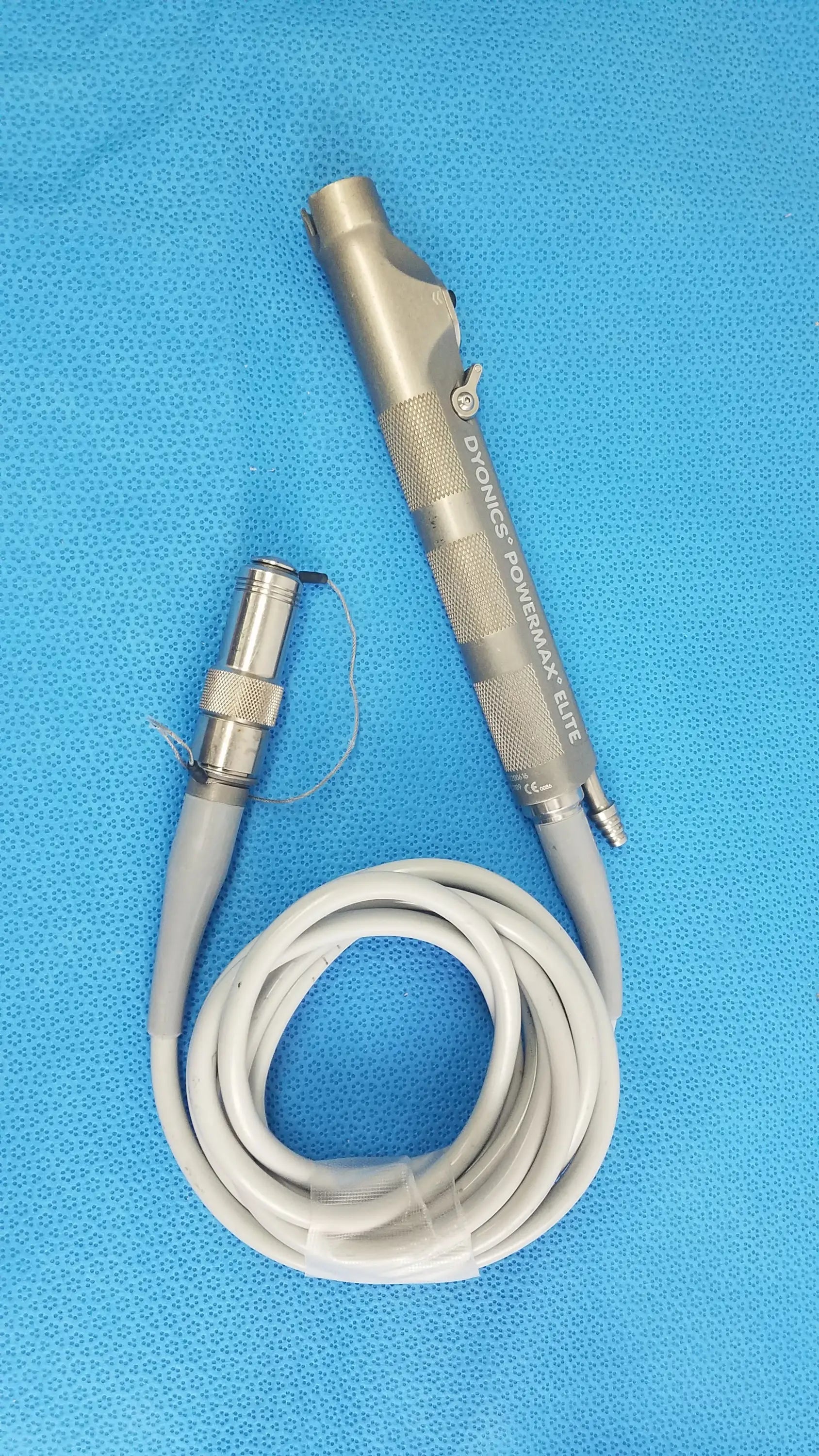 Silver metallic dyonics powermax elite shaver handpiece with textured grip and coiled gray cable for medical equipment use