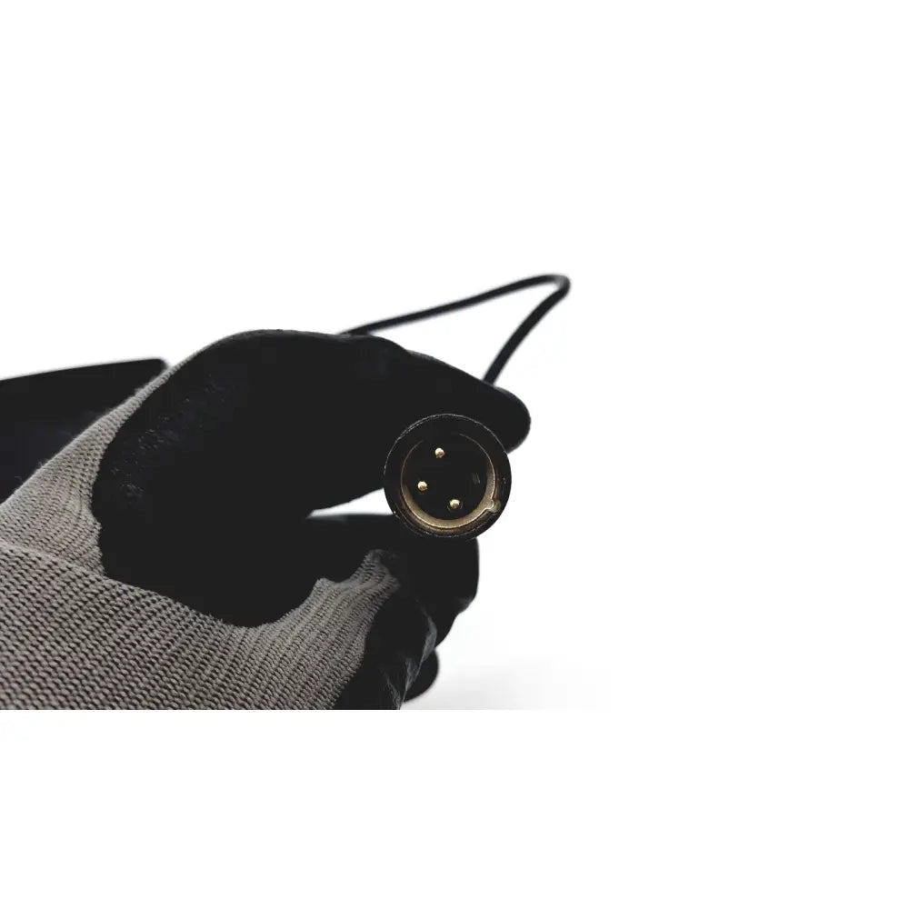 Black-gloved hand holding black xlr audio cable connector with three gold-plated pins for eds adaptor charger reuse medical