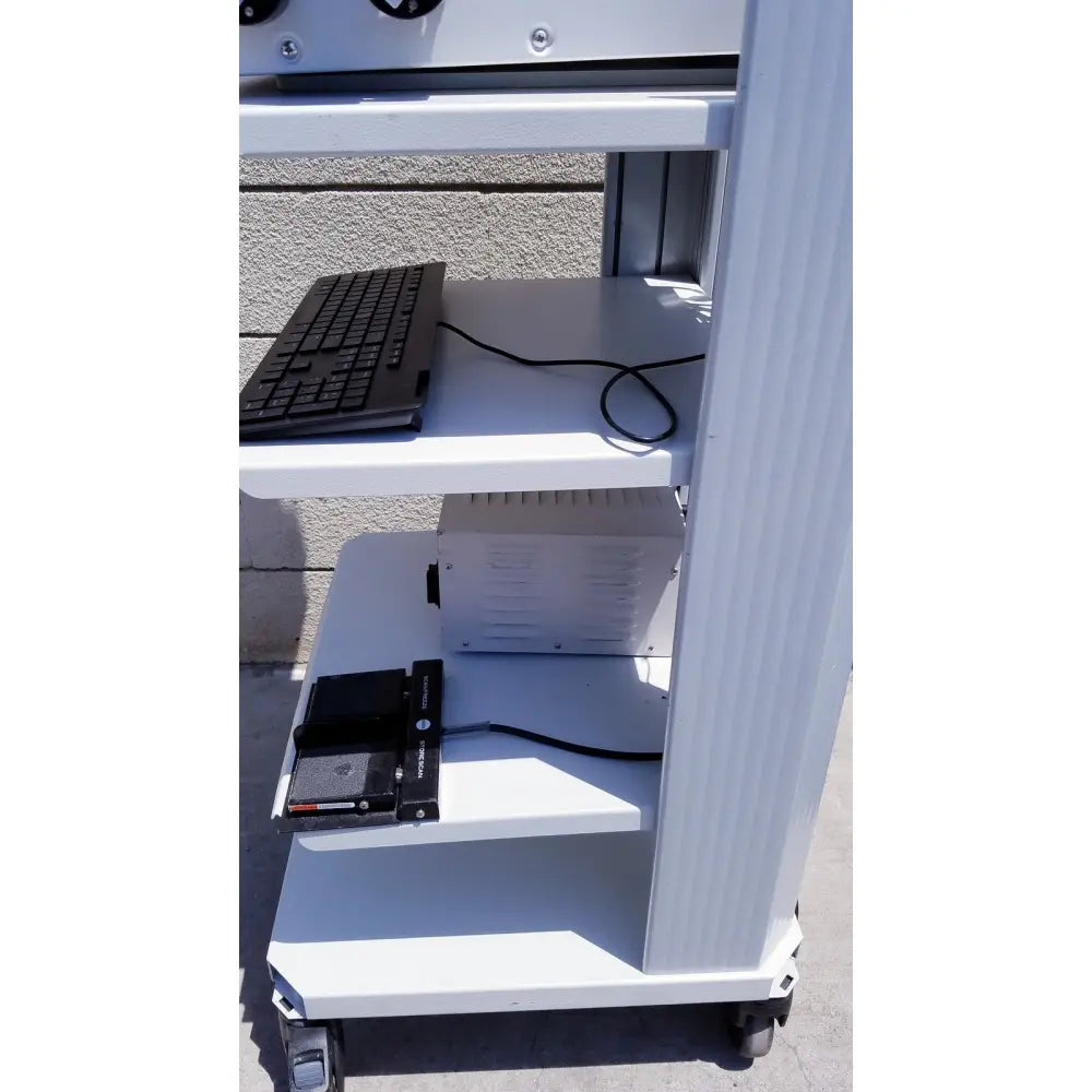 White metal cart with three shelves holding black keyboard and white device for ellex eyecubed ultrasound biomicroscopy system