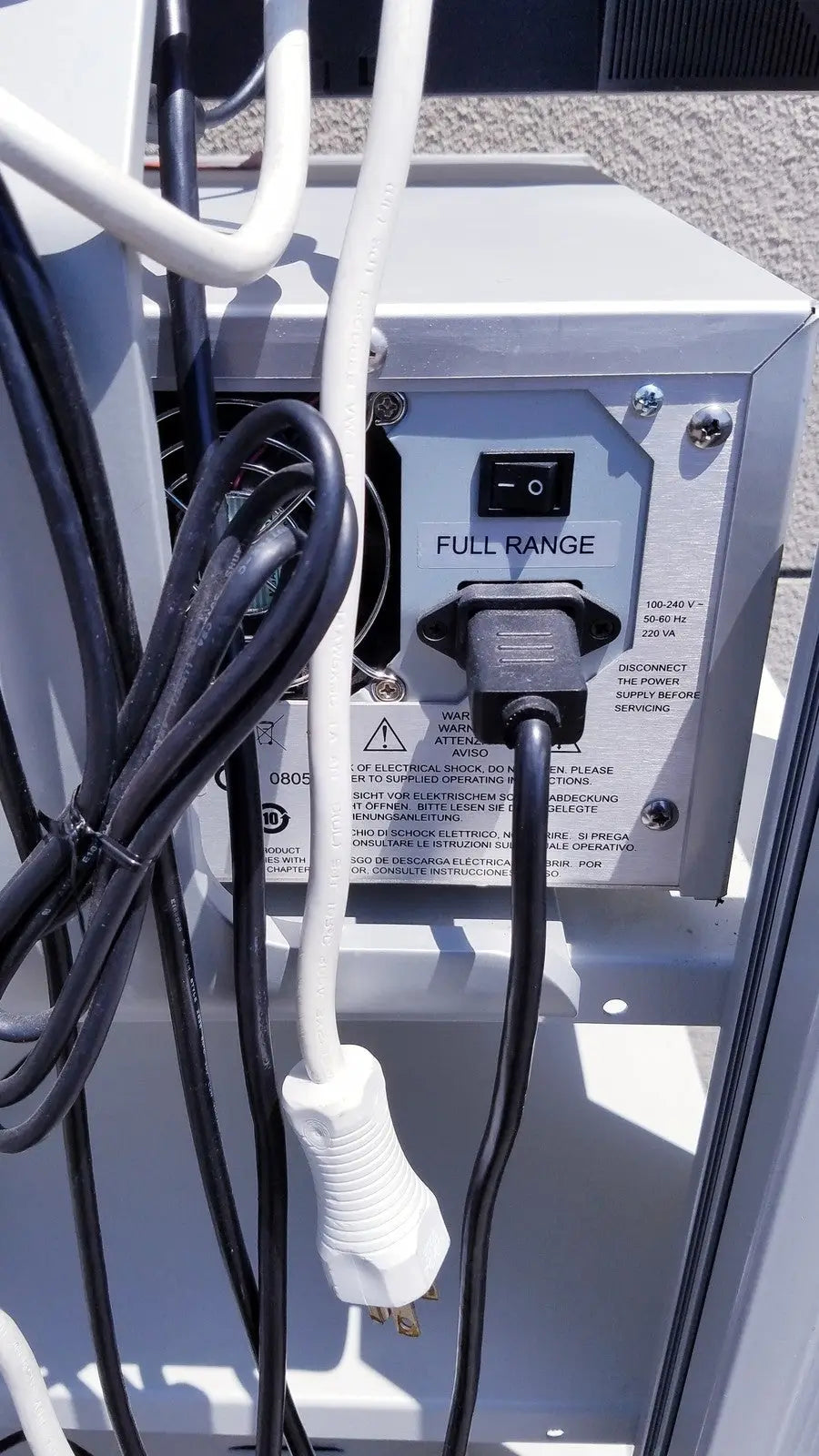 Black electrical plug connected to white power cord on the back panel of gray ellex eyecubed ultrasound biomicroscopy system