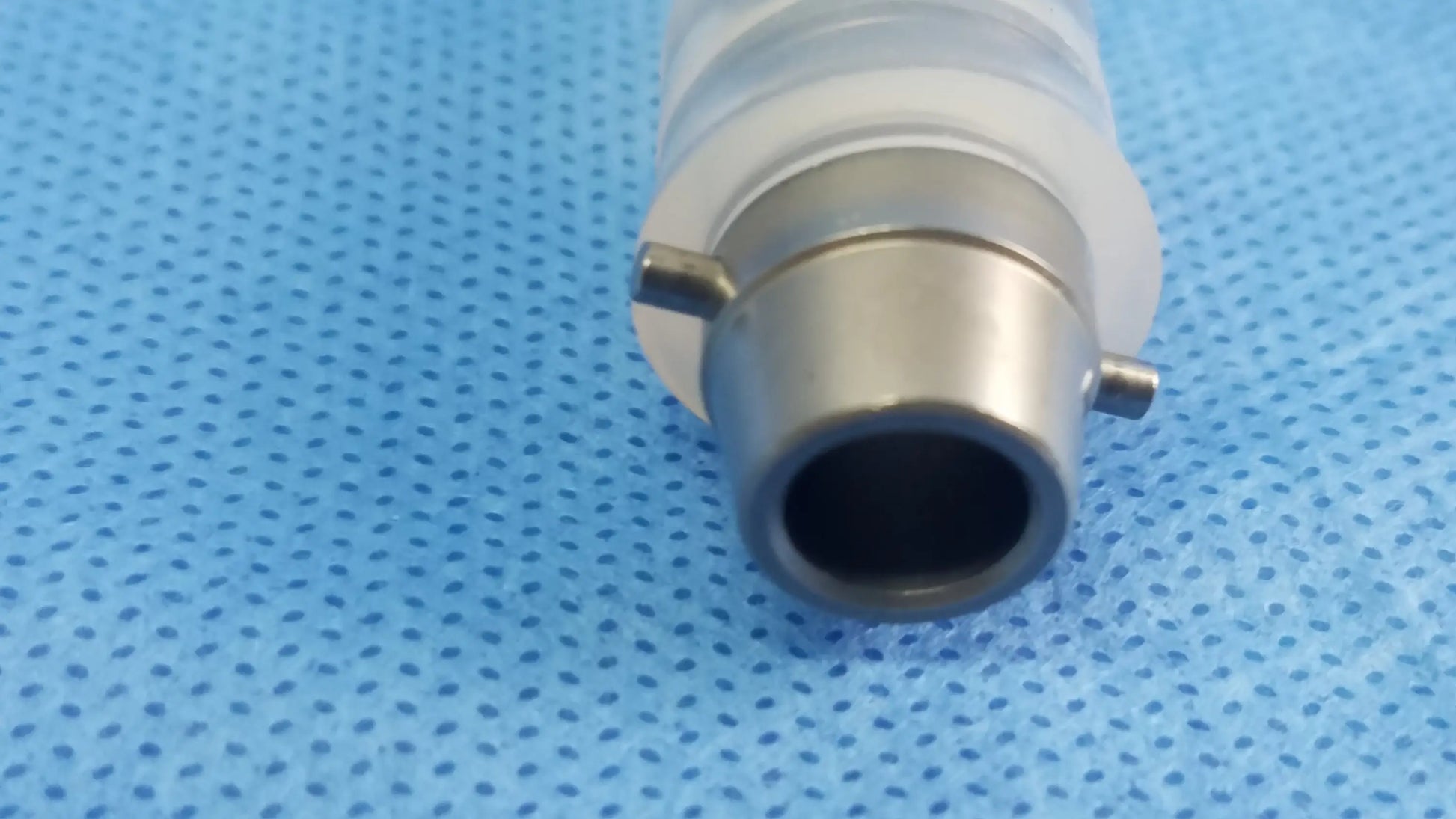 Translucent white ellik evacuator adapter with metallic silver base and tabs compatible with endoscopic systems