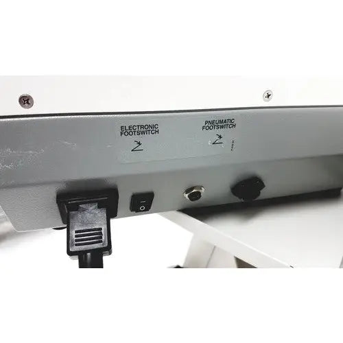 The back side of the ellman surg-e-vac surgical smoke evacuation system svd110 displays a silver metal panel with two labeled footswitches and an electrical plug connected for surgical smoke evacuation