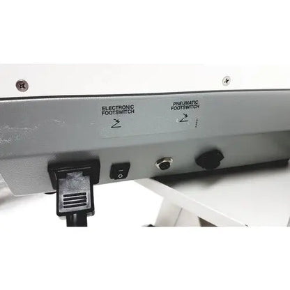 The back side of the ellman surg-e-vac surgical smoke evacuation system svd110 displays a silver metal panel with two labeled footswitches and an electrical plug connected for surgical smoke evacuation
