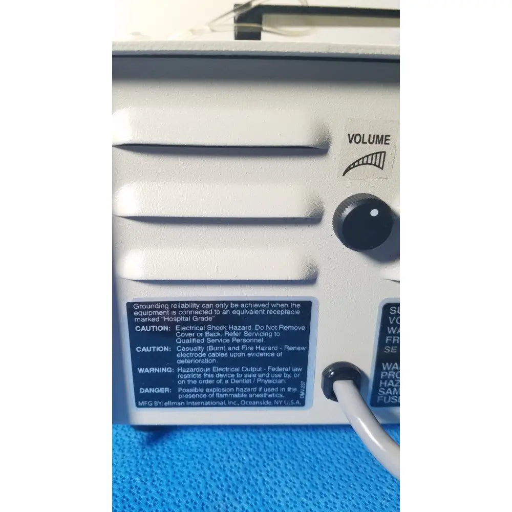 White plastic ellman surgitron emc electrosurgical unit with black volume knob and warning labels for medical use