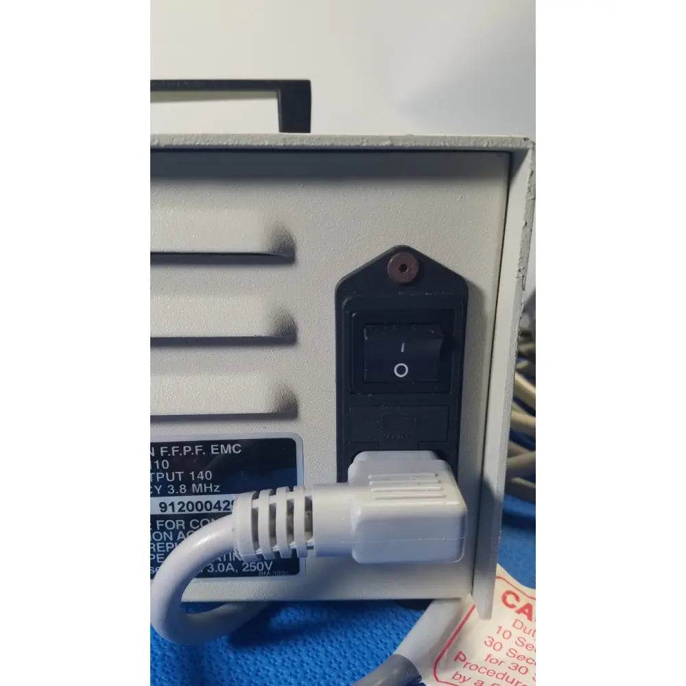 Gray metal power supply unit with black switch and white plug connected shown from the back of ellman surgitron emc electrosurgical unit