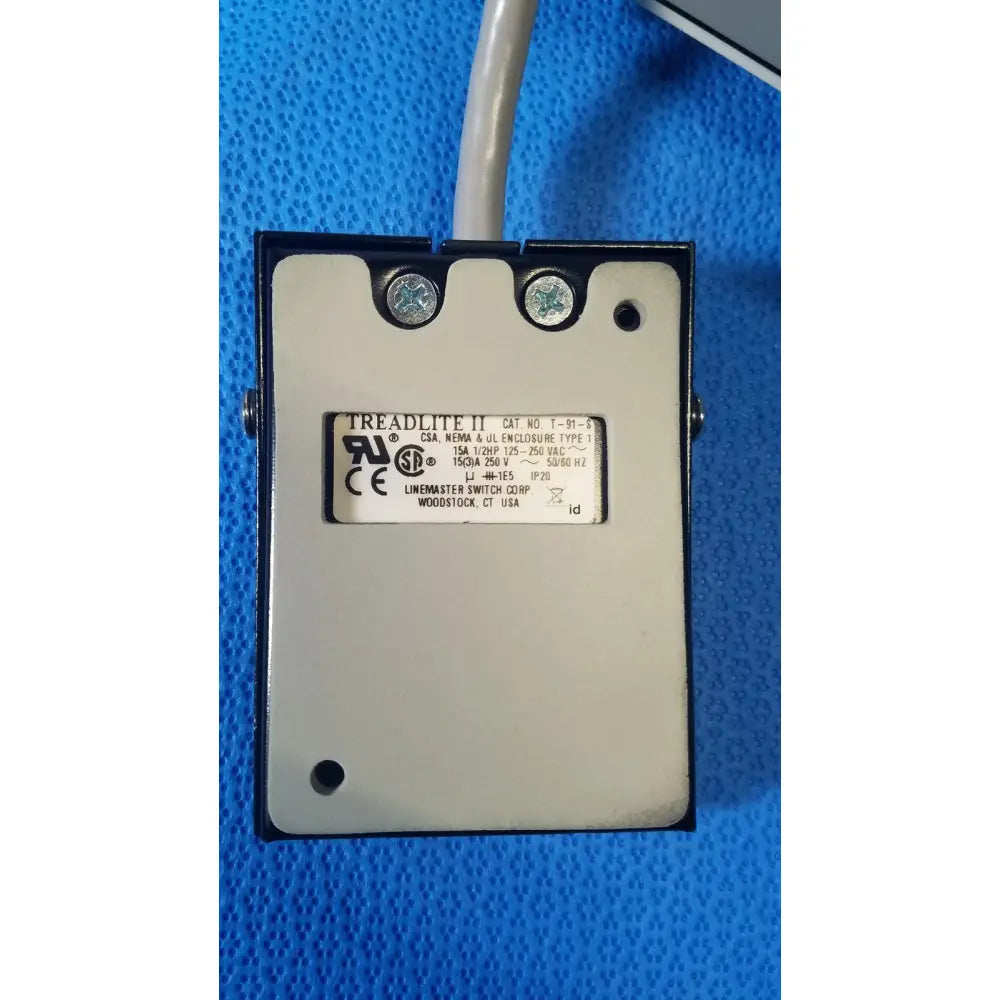 Black rectangular industrial switch labeled treadlite ii with specifications on white label for ellman surgitron emc electrosurgical unit