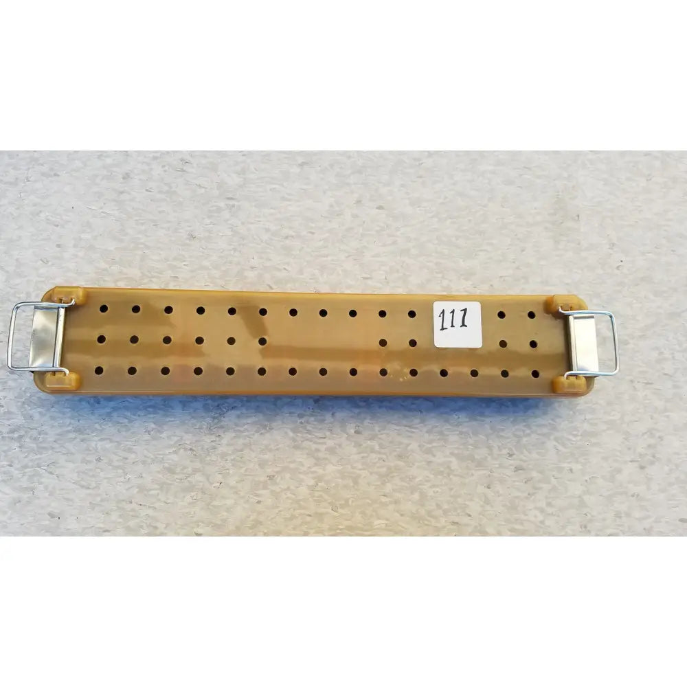 Tan plastic pegboard with metal clasp ends and white label 117 for endoscope sterilization case tray