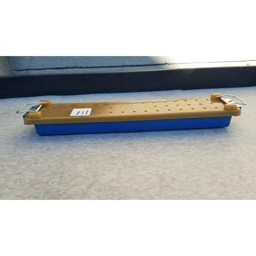 Blue and tan plastic sharpening stone with metal clamps for secure use in an endoscope sterilization case tray