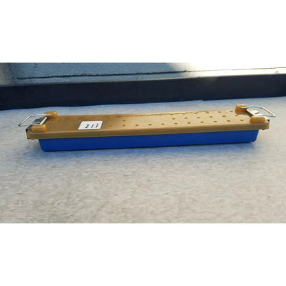 Blue and tan plastic sharpening stone with metal clamps for secure use in an endoscope sterilization case tray
