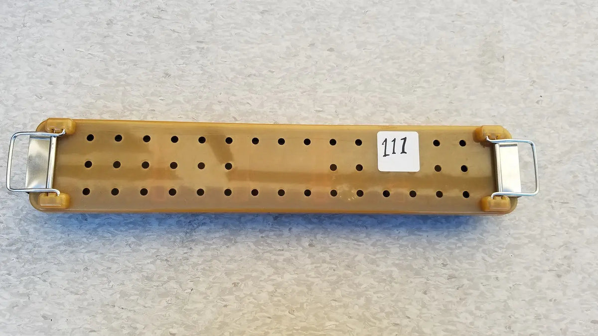 Tan plastic pegboard with metal clasp ends and white label 117 for endoscope sterilization case tray