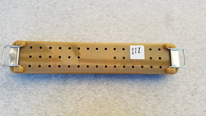 Tan plastic pegboard with metal clasp ends and white label 117 for endoscope sterilization case tray