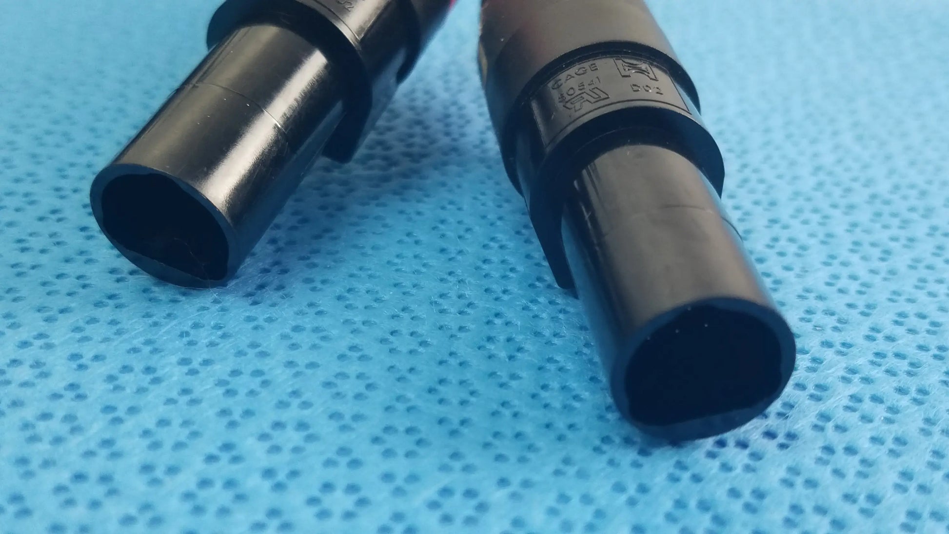 Black plastic cylindrical medical equipment with matte finish and engraved markings for reuse catheter connector cable