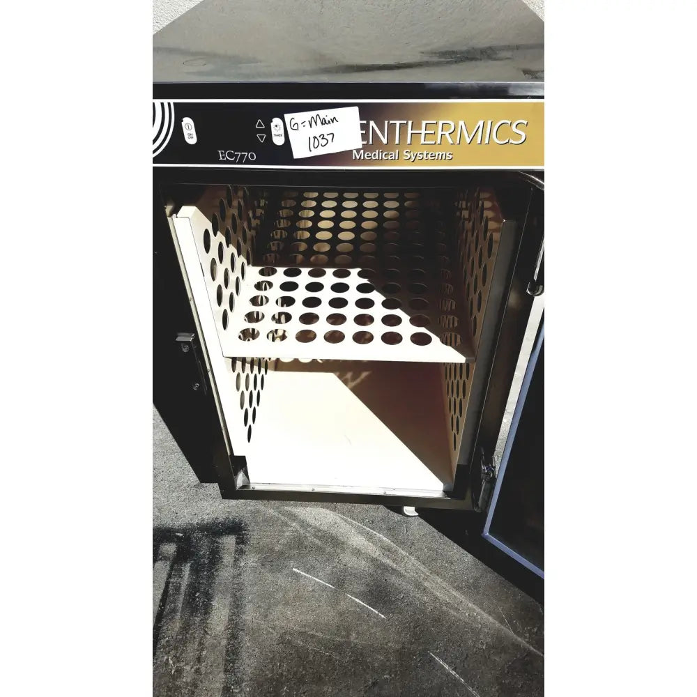 Black industrial sterilizer with perforated metal interior and white plastic shelf by enthermics medical systems ec770 fluid warmer