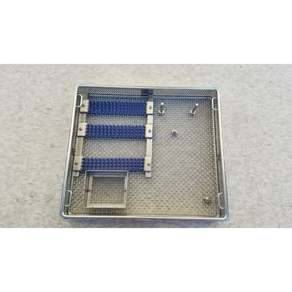 Entific sterilization case tray in stainless steel with three blue rubber grips and multiple metal pins for instruments