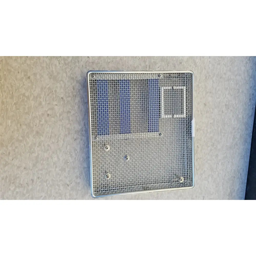Silver mesh ventilation grille with rectangular frame and three blue panels on entific sterilization case tray