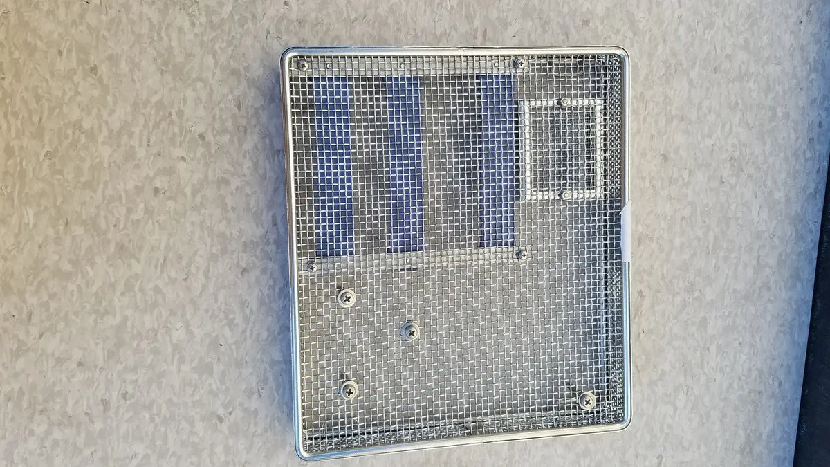 Silver mesh ventilation grille with rectangular frame and three blue panels on entific sterilization case tray