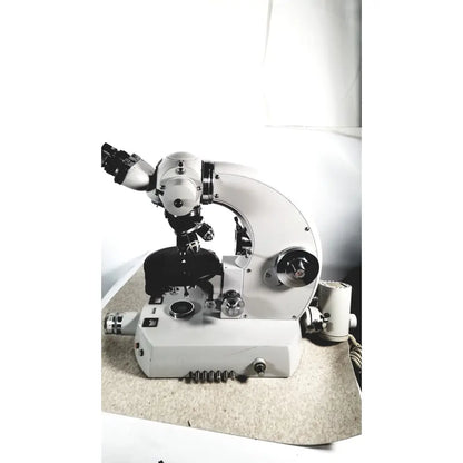 White compound microscope with black mechanical parts and adjustable focus used alongside eppendorf centriifuge for medical reuse