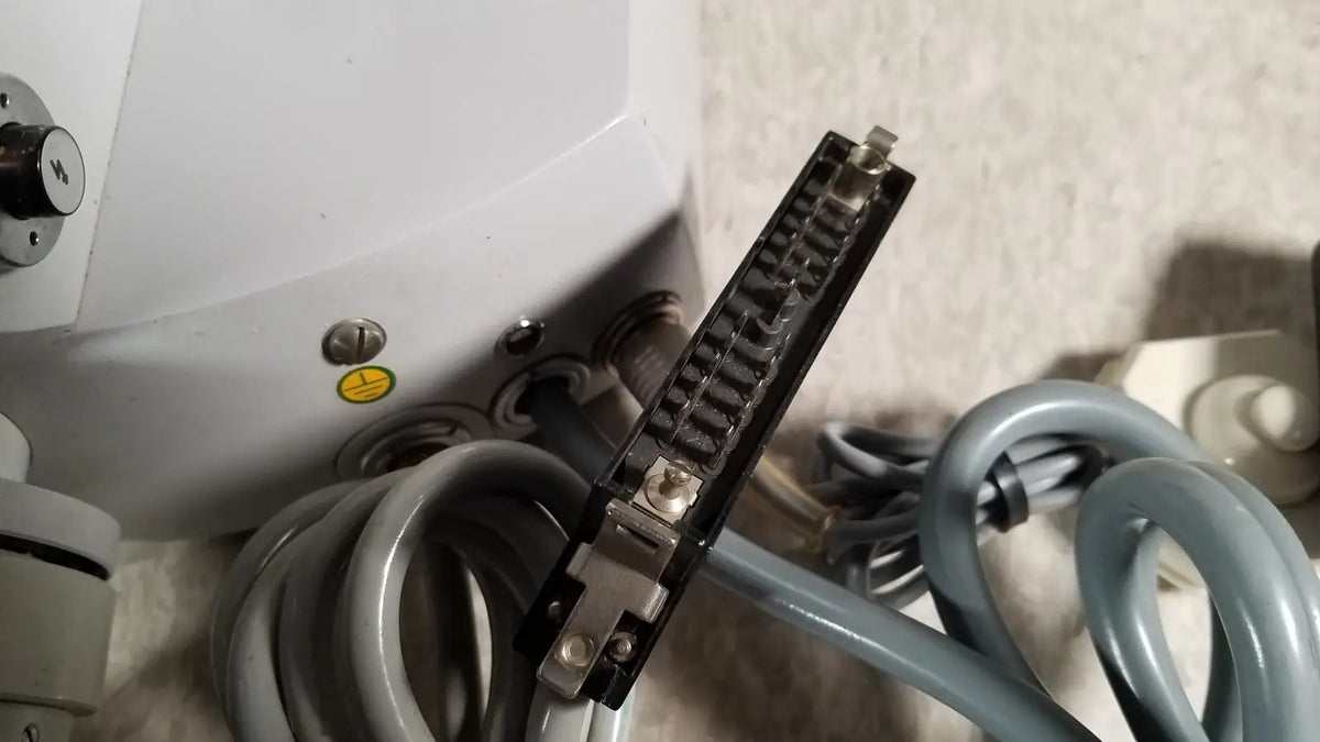 Black rectangular connector with metallic pins and silver screws attached to gray coiled tubing on eppendorf centrifuge 5415 r reuse medical component