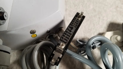 Black rectangular connector with metallic pins and silver screws attached to gray coiled tubing on eppendorf centrifuge 5415 r reuse medical component
