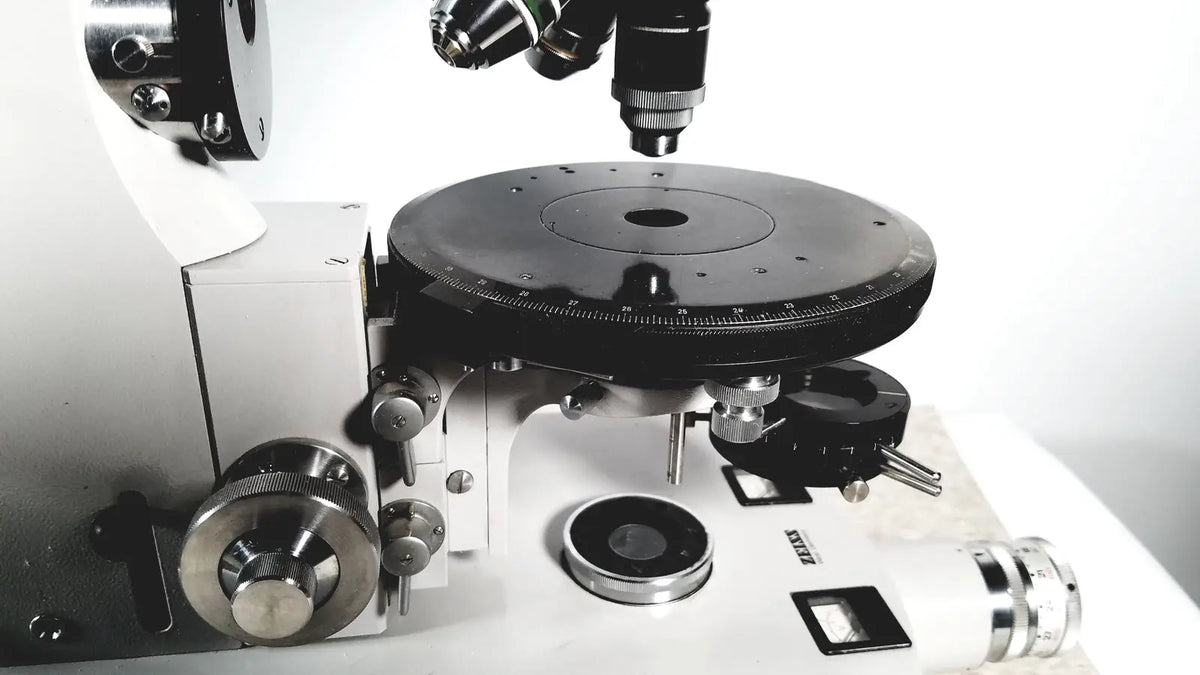 Black and silver compound microscope with rotating stage and lenses shown with eppendorf centriifuge 5415 R for reuse medical applications