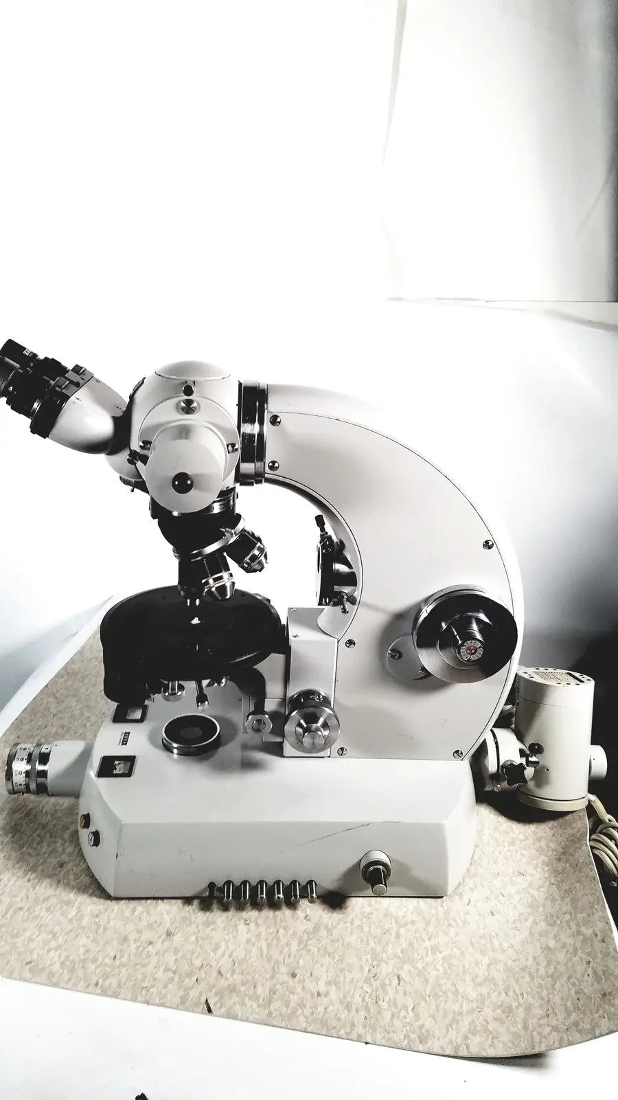 White compound microscope with black mechanical parts and adjustable focus used alongside eppendorf centriifuge for medical reuse