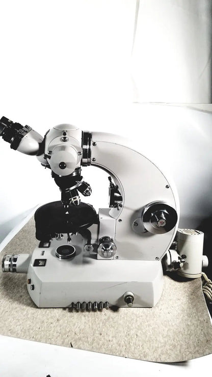 White compound microscope with black mechanical parts and adjustable focus used alongside eppendorf centriifuge for medical reuse
