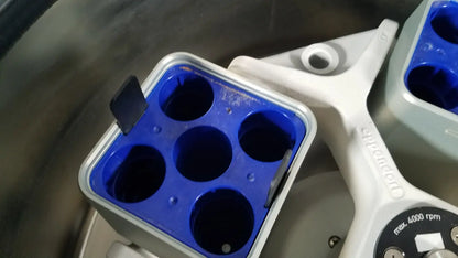 Blue plastic sample holder with six wells mounted on white eppendorf centriifuge model 5810 arm for reuse medical labs