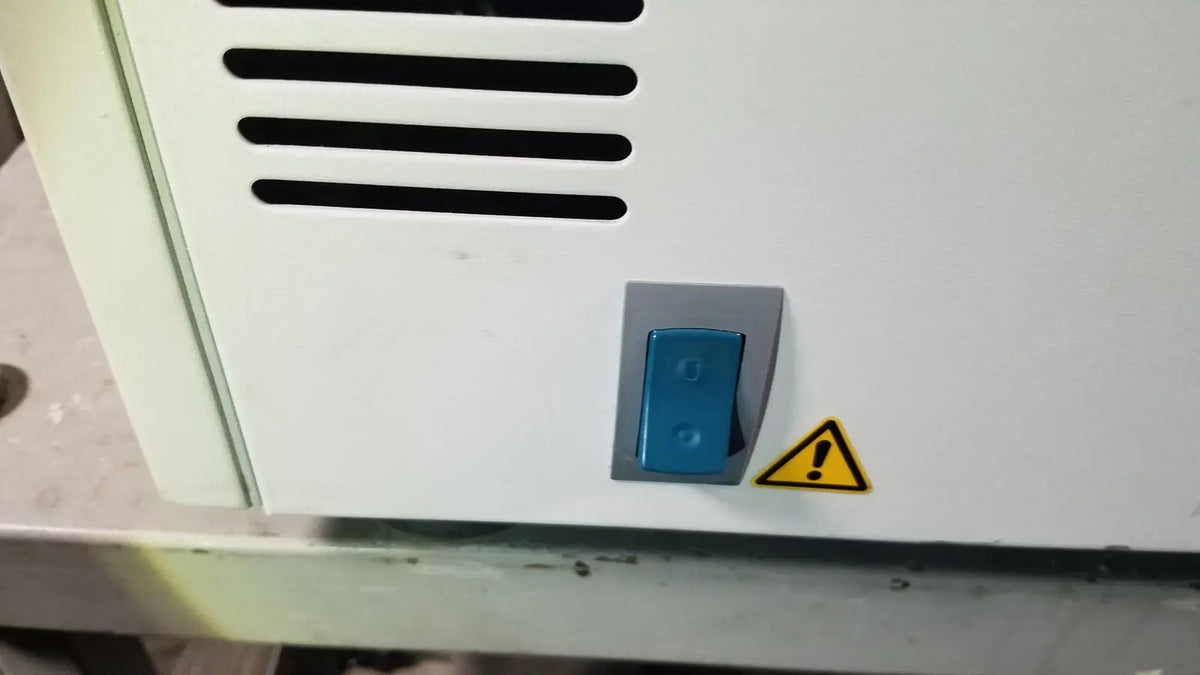 Blue toggle switch with gray housing on white appliance panel of eppendorf centriifuge model 5810 for reuse medical purpose