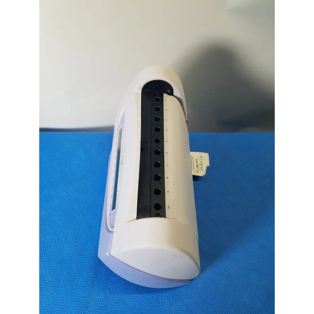 White plastic nail dryer with black circular slots and small label on the side of excyte m automated esr analyzer