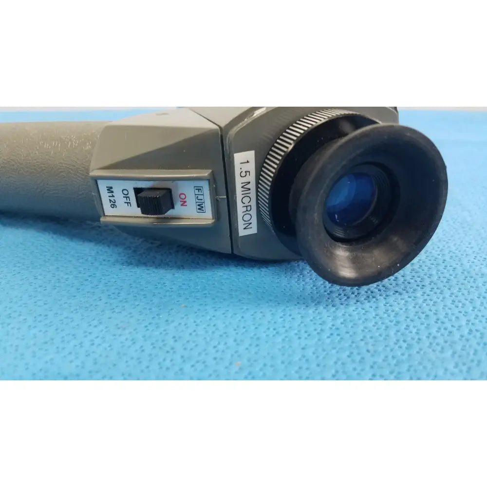 Gray and black handheld microscope with textured grip labeled 1.5 micron by FJW Optical Systems optical systems