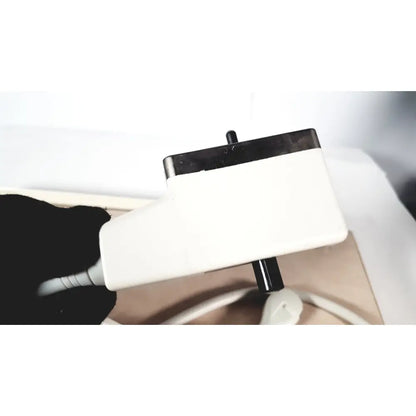 White rectangular power adapter with black top and usb port held by gloved hand for fukuda denshi ultrasound probe trans vaginal use