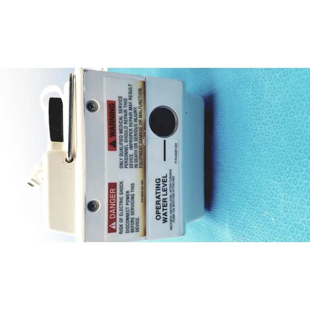 White plastic gaymar t pump tp500c heat therapy pump with black circular water level indicator and warning labels visible