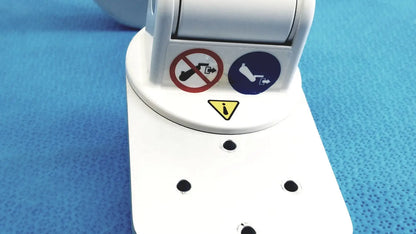 White plastic gcx vhm variable height arm medical device with warning labels and mounting holes visible on back side