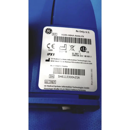Blue ge carescape dinamap v100 vital signs monitor with white certification label and serial number visible on back side