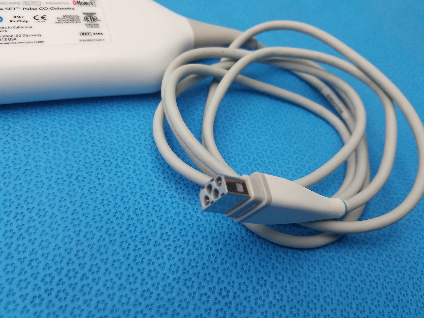 White plastic GE Carescape SpO2 Masimo Rainbow set pulse oximeter with coiled gray cable and multi-pin connector