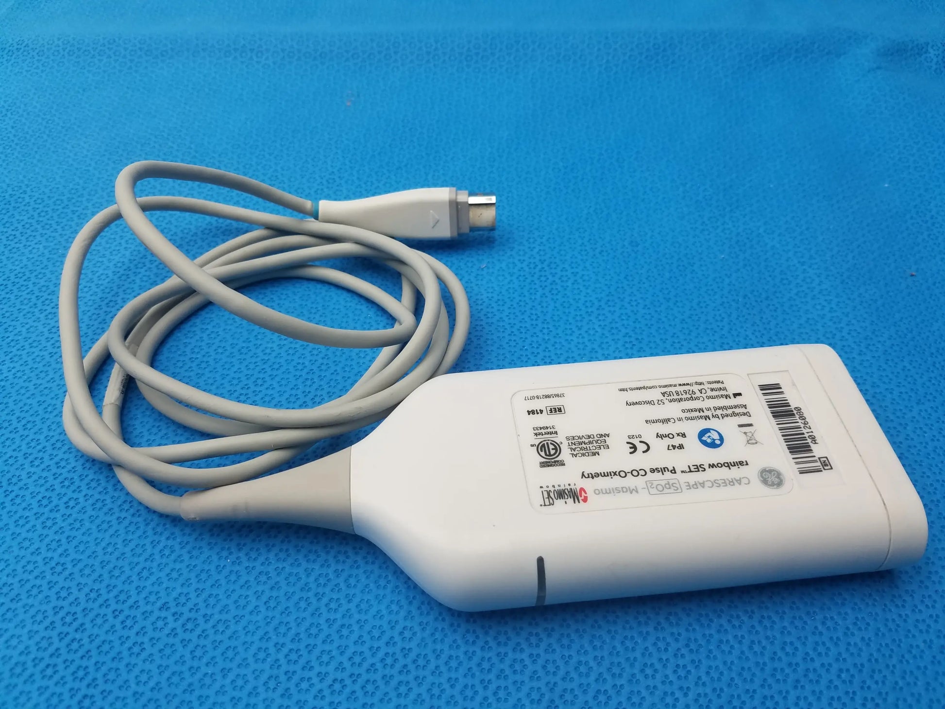 White plastic ultrasound transducer with coiled gray cable and metallic connector back labeled ge carefusion for masimo rainbow set