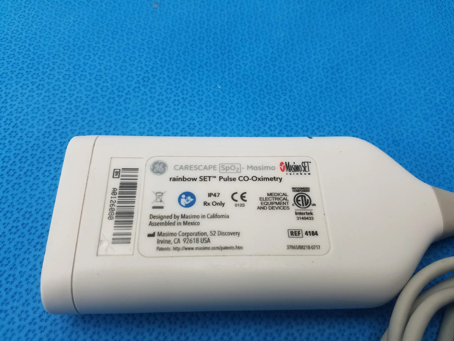 White plastic pulse oximeter labeled masimo rainbow set for ge carescape spo2 pulse co-oximetry parameter ref 4184