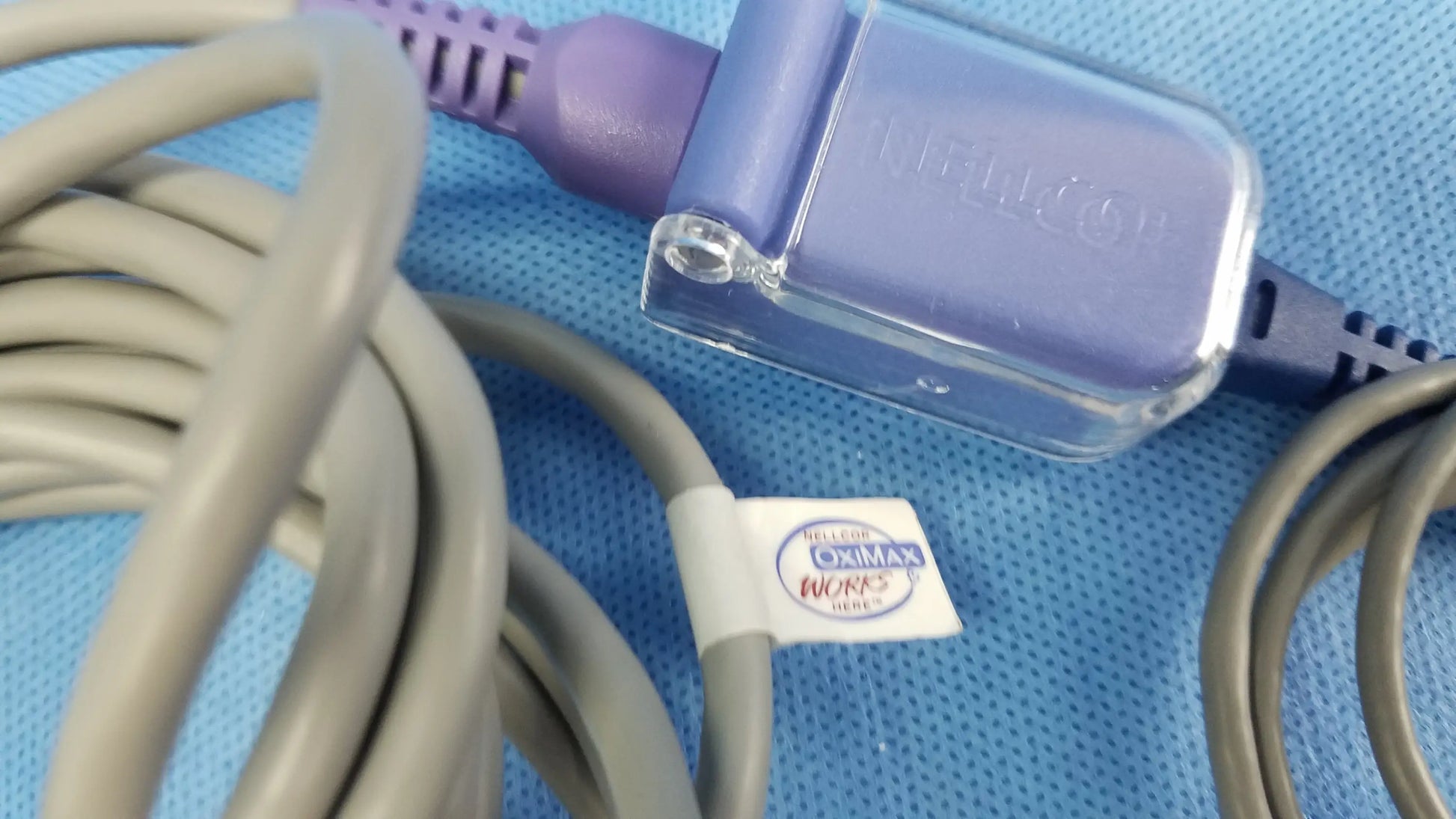 Ge dinamap v100 vital signs monitor connector with purple and clear plastic and gray coiled cable labeled nellcor for nibp cuffs and power adapter