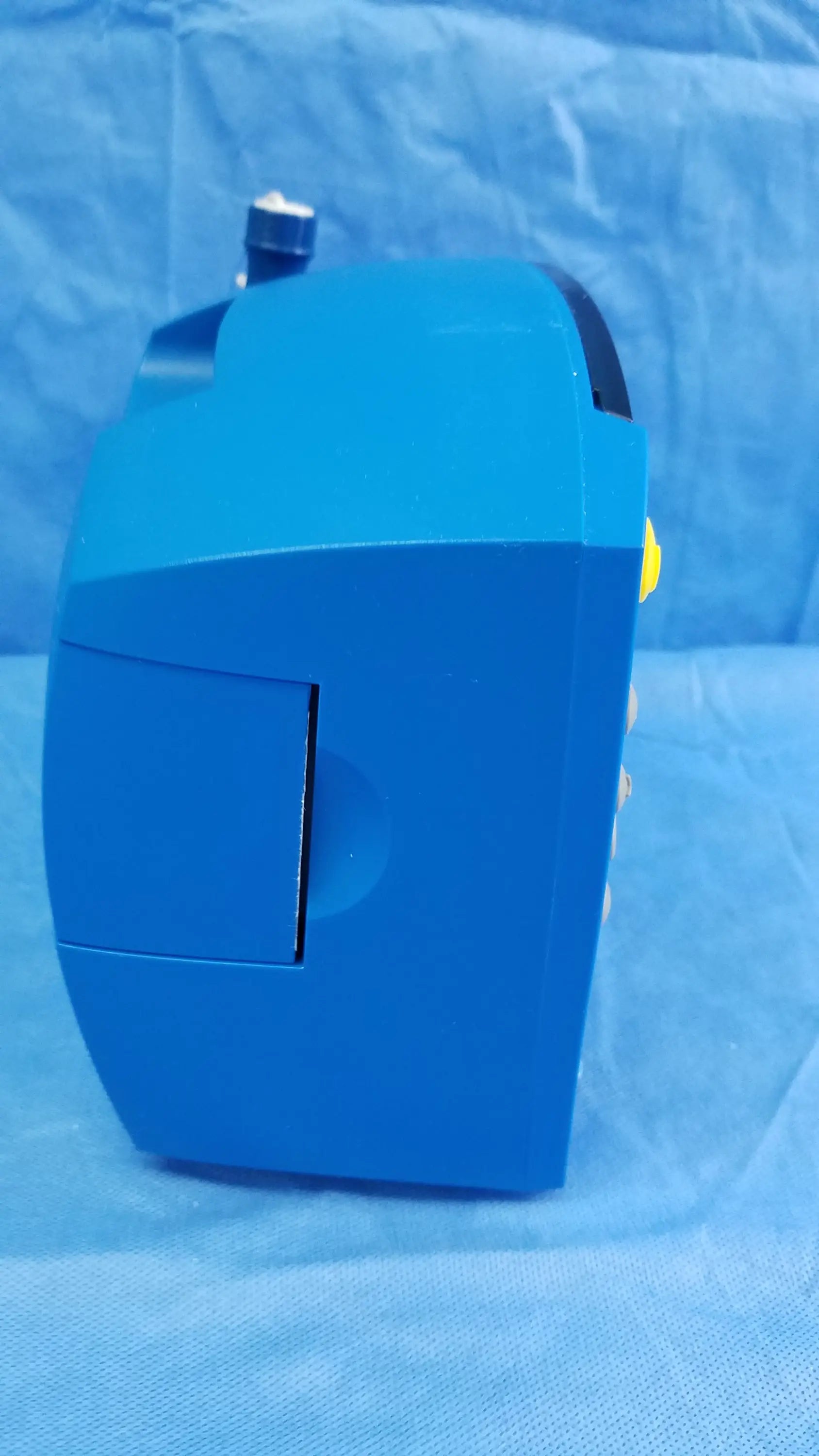 Blue plastic toy robot with yellow accents and black top shown alongside ge dinamap v100 vital signs monitor with nibp cuffs and power adapter