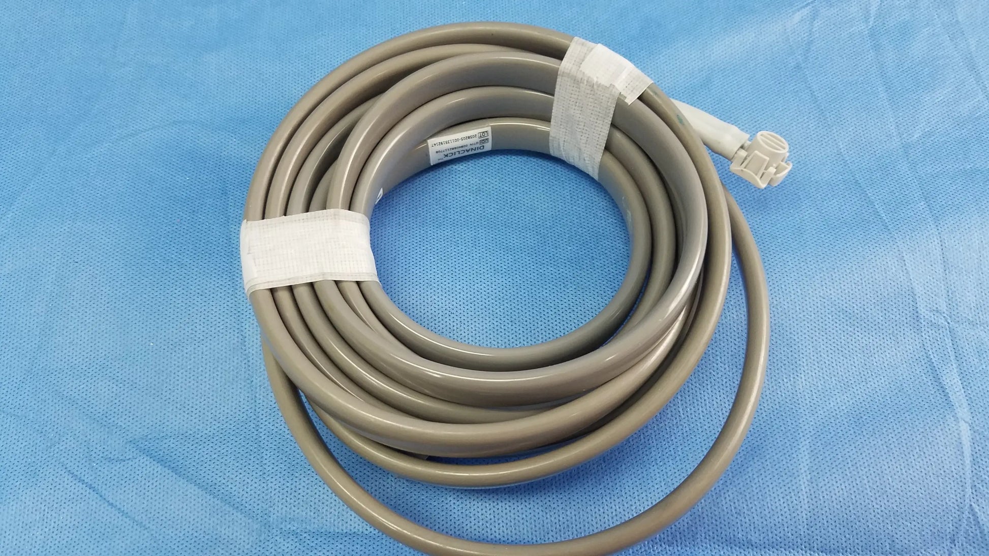 Gray coiled medical cable with white connector and tape securing loops for ge dinamap v100 vital signs monitor accessories including nibp cuffs and power adapter