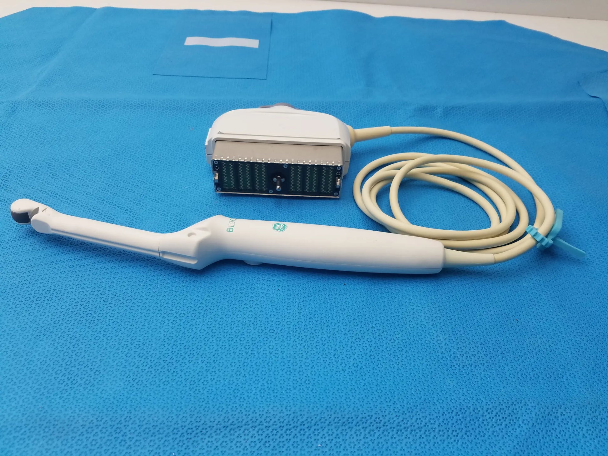 White ge healthcare be9cs-d bi-plane micro convex ultrasound probe with coiled beige cable and green logo on handle