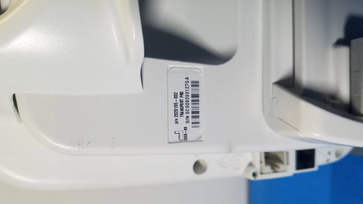 White plastic security camera with barcode label and serial number on the back of ge healthcare transport pro patient monitor