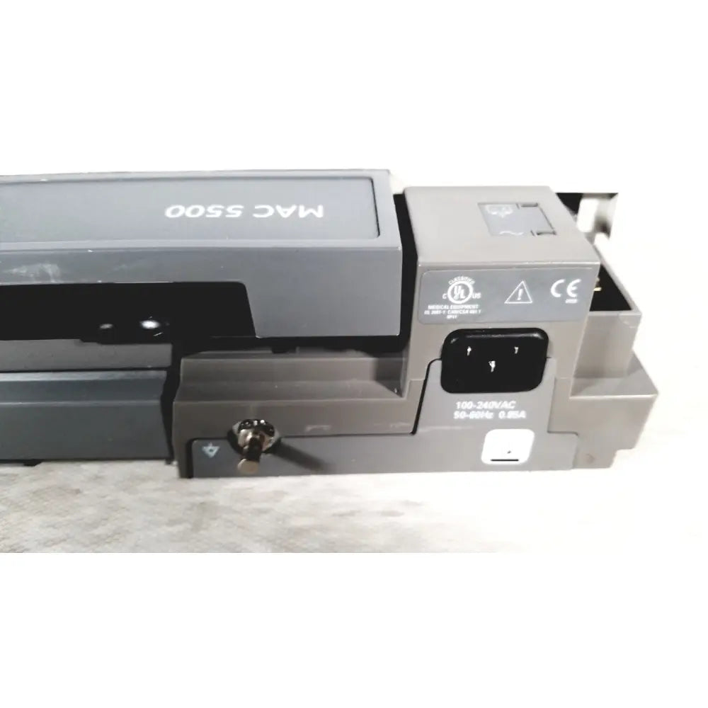 Back side of gray ge mac 5500 hd resting electrocardiogram ecg machine showing power input port and certification labels